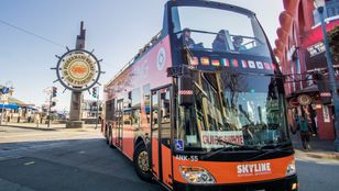 Excited tourists savoring their bus journey on the vibrant Orange Skyline Sightseeing in the lively streets of San Francisco.